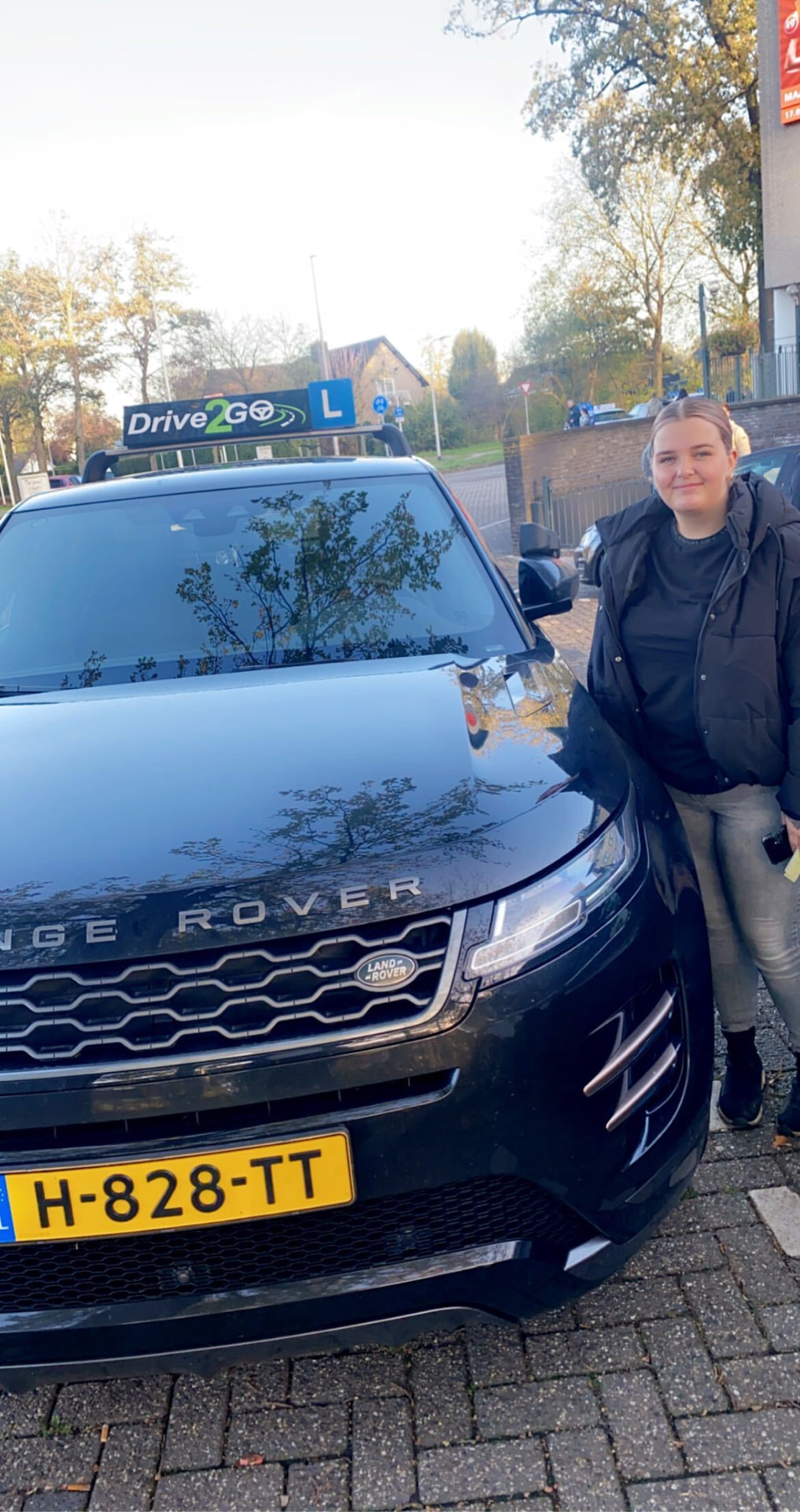 Geslaagde leerling bij de lesauto van Drive2Go